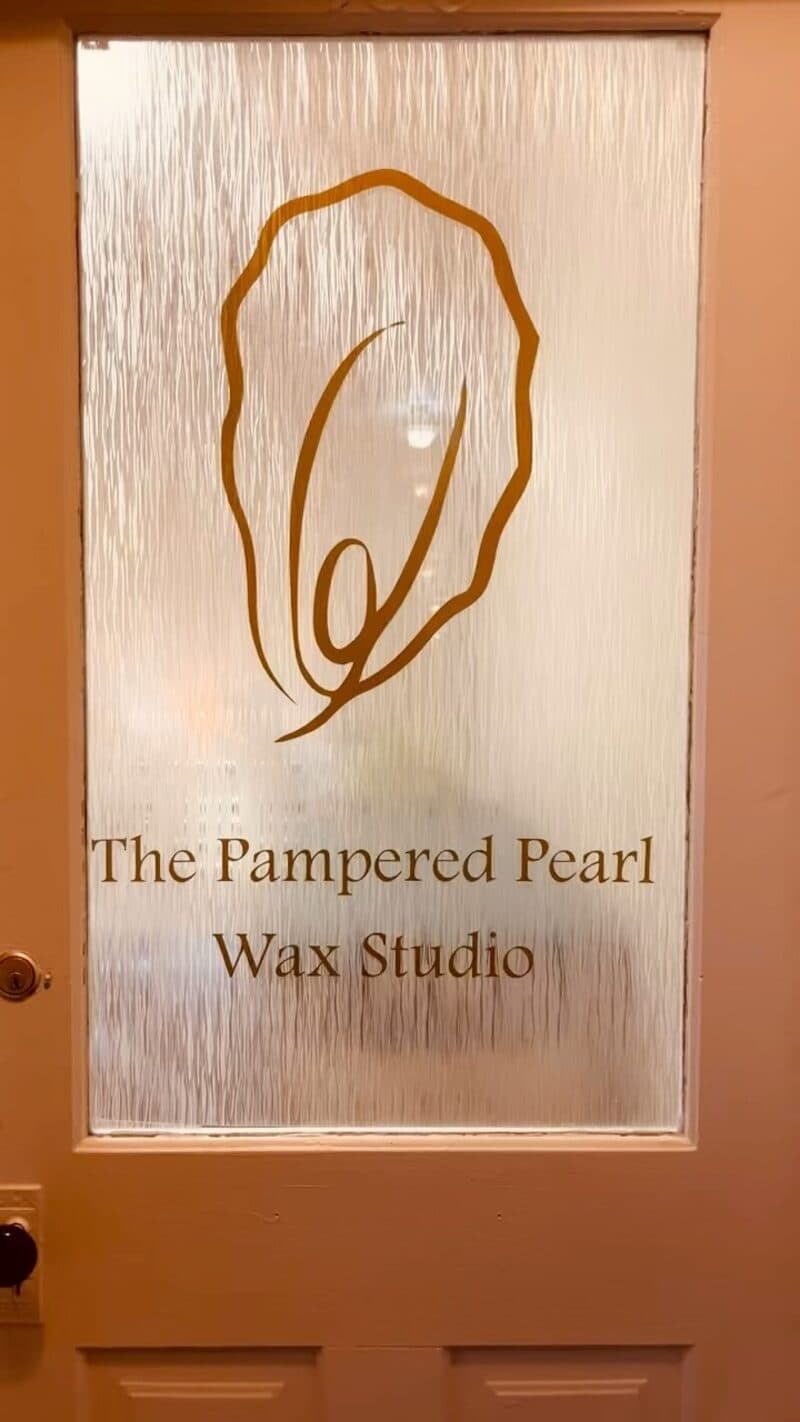 The etched-glass front door of The Pampered Pearl Wax Studio